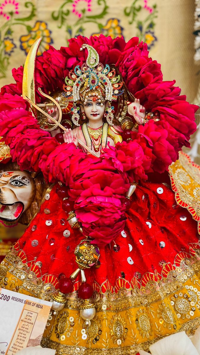 a woman dressed in red and gold is standing next to a mask on her head