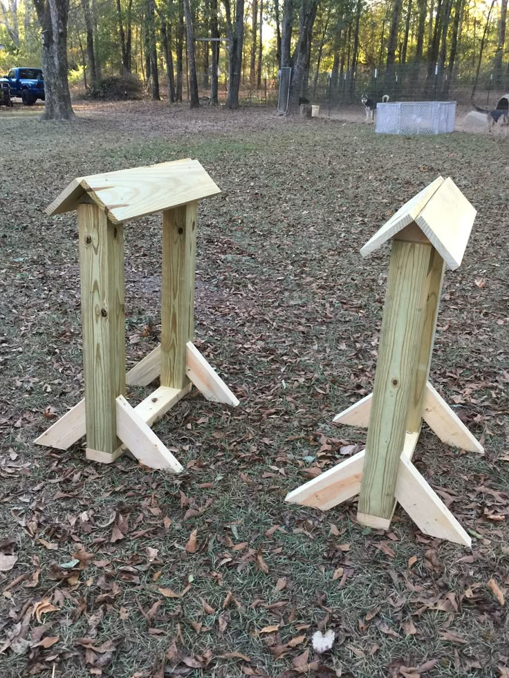 two wooden bird houses sitting in the grass