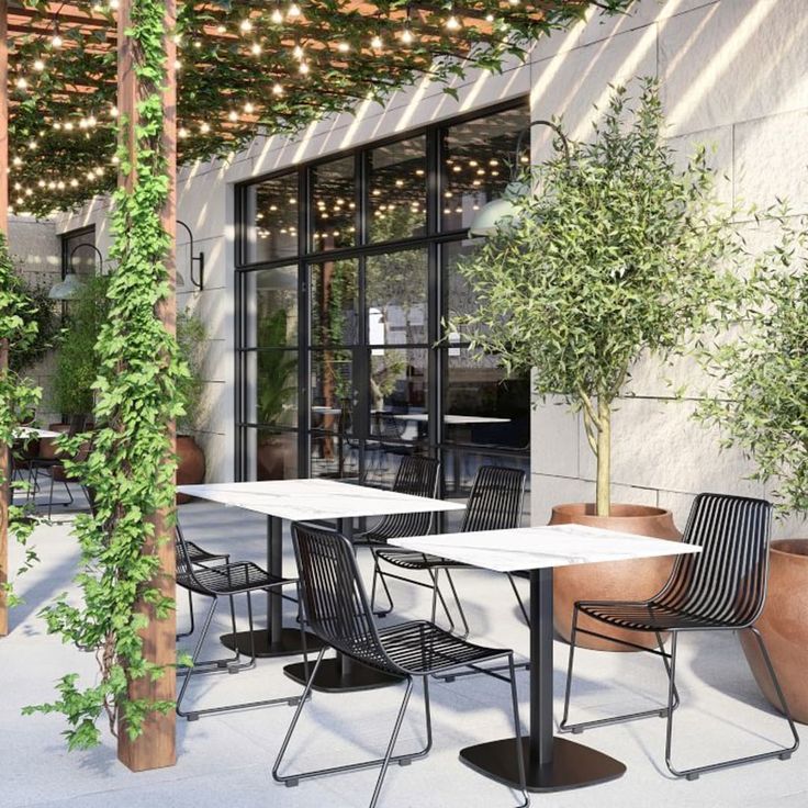 an outdoor dining area with tables, chairs and potted plants on the outside patio