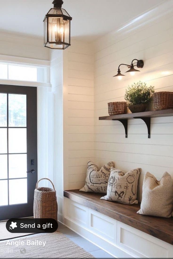 the entryway is decorated in white and has wooden shelves with baskets on them, along with decorative pillows