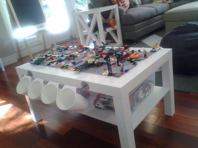 a table with legos on it in the middle of a living room and a couch