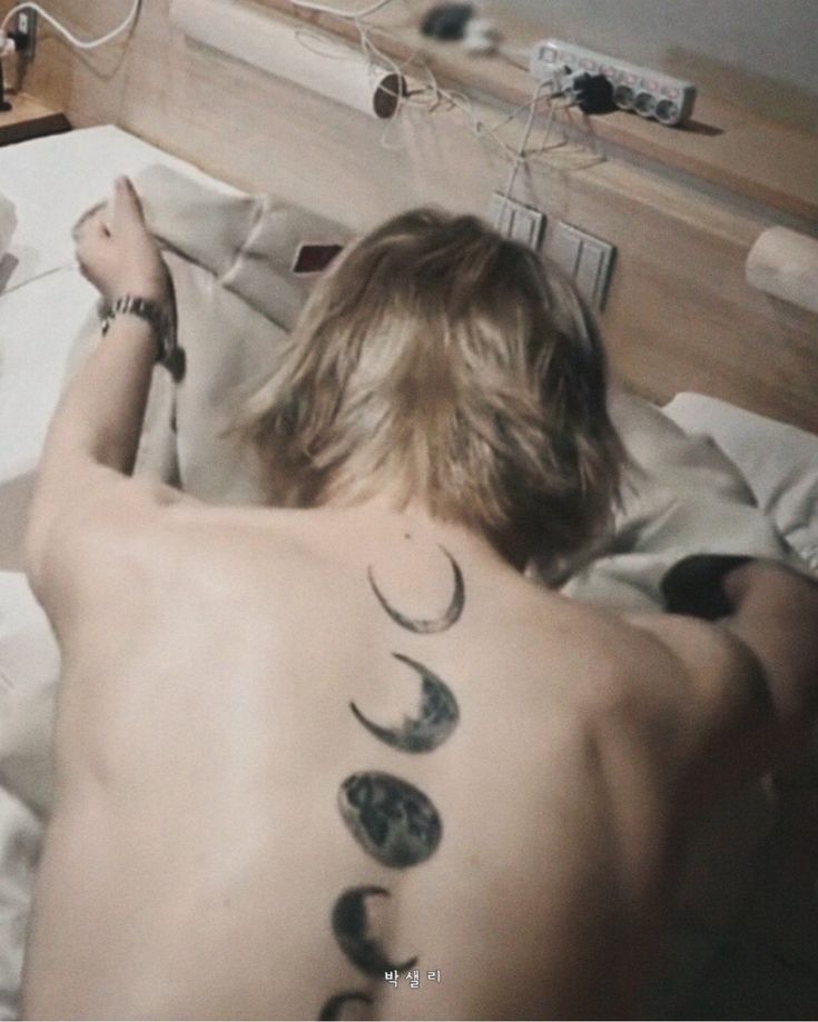 a man laying in bed with tattoos on his back