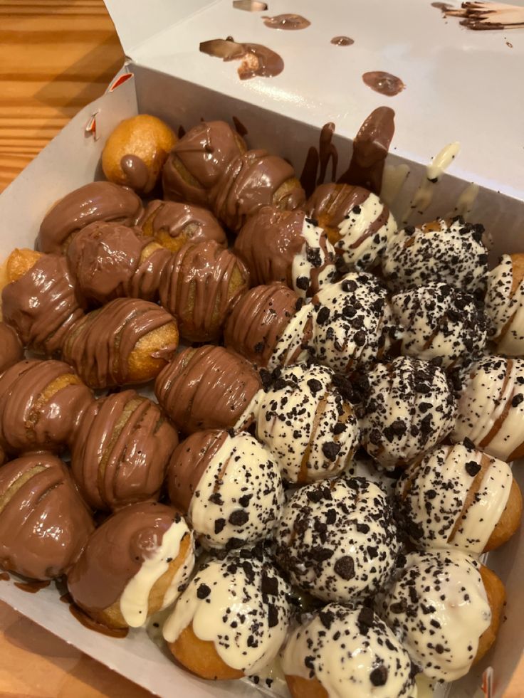 a box filled with lots of different types of donuts on top of a wooden table