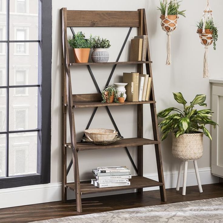 a wooden shelf with books and plants on it in front of a window, next to a potted plant