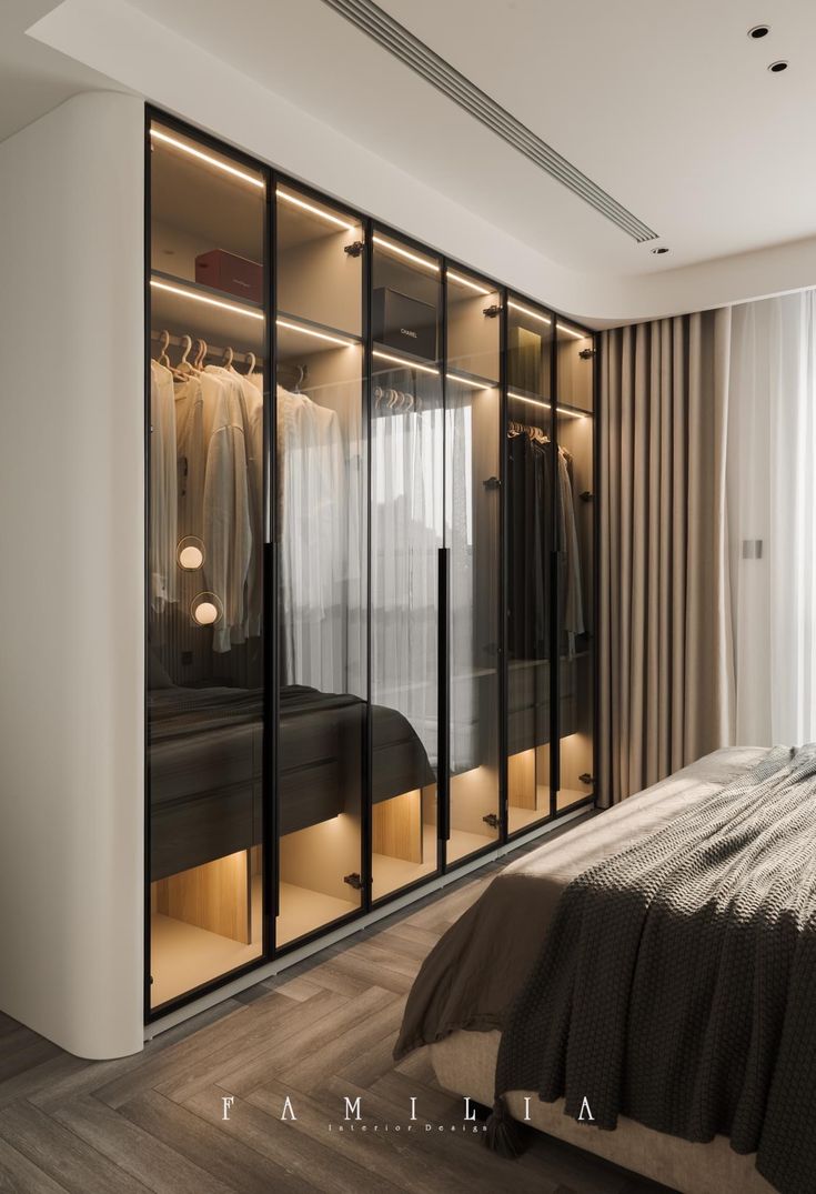 a bedroom with a bed and closets next to a window that has curtains on it