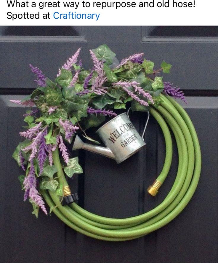 a green hose attached to a black door with purple flowers and greenery on it