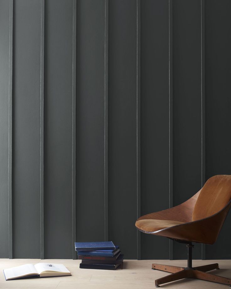 a chair and some books on the floor in front of a wall with vertical stripes