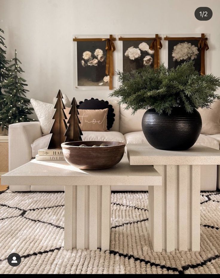 a living room filled with furniture and christmas trees on top of the coffee table in front of a white couch