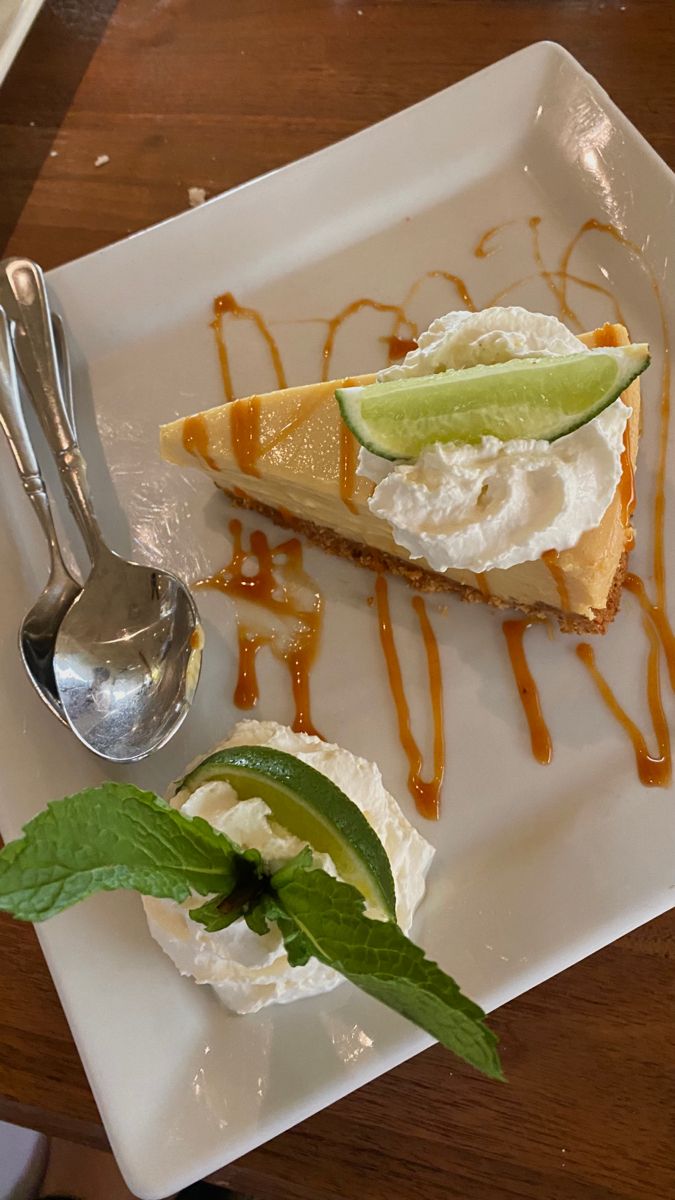 a piece of pie on a plate with ice cream and lime wedges next to it