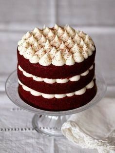 a red velvet cake with white icing on a glass plate and lace doily