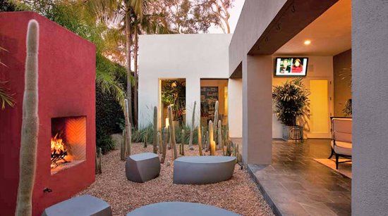 an outdoor living area with fire place and cactus trees in the backgrounge