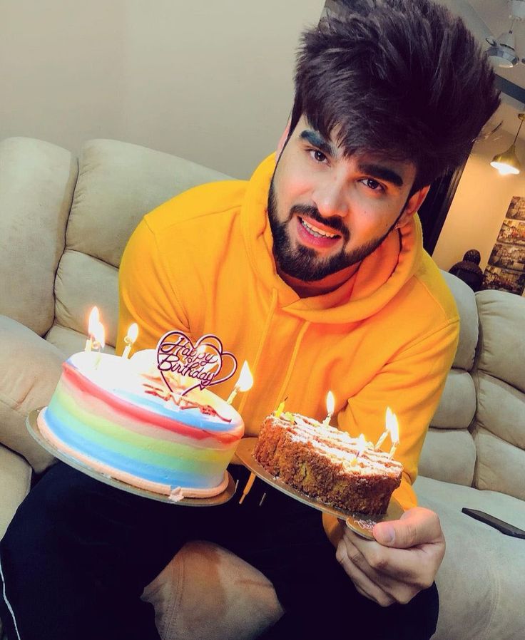 a man sitting on a couch holding a cake with lit candles