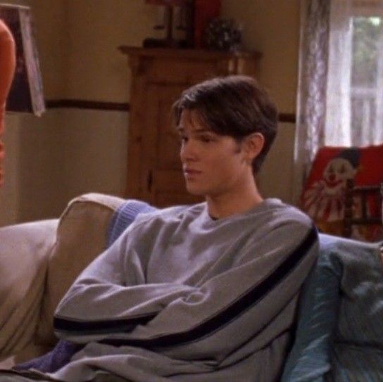 a young man wrapped in a blanket sitting on a couch