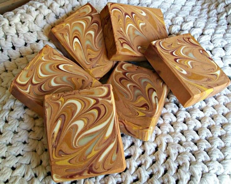 four wooden blocks sitting on top of a white knitted rug with brown and yellow swirled designs