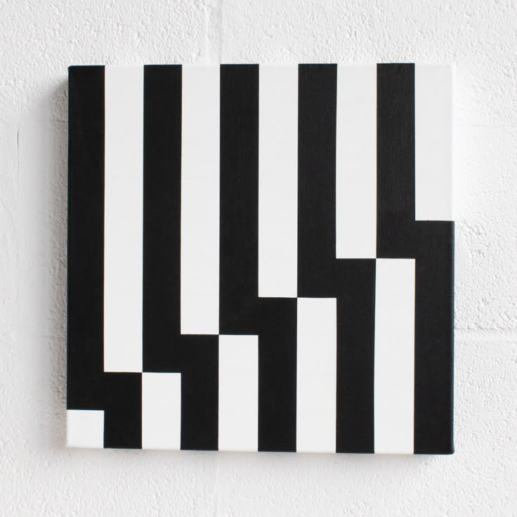 a black and white painting hanging on the side of a wall with vertical lines painted on it