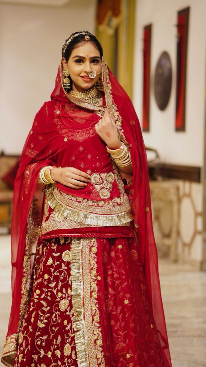 a woman in a red and gold bridal gown with her hand on her hip