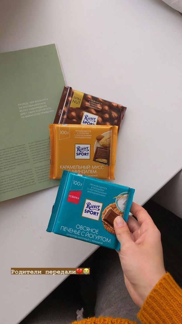 a person holding some kind of chocolate bar in front of two other bars on a table