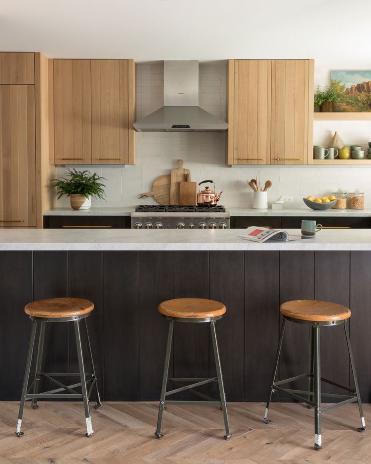 three stools are in front of the kitchen island with an island countertop and wooden cabinets