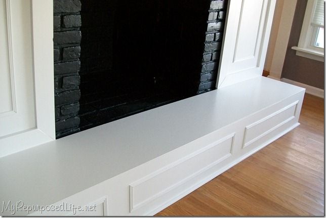 an empty fireplace with white mantle and black brick