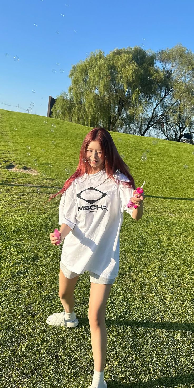 a girl with red hair is standing in the grass