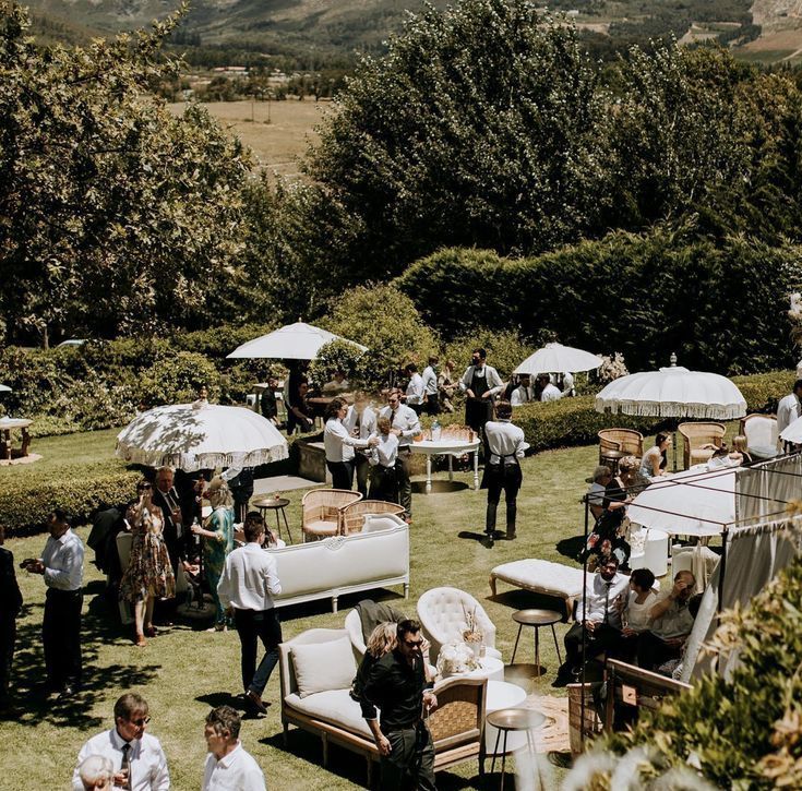 a group of people sitting on top of a lush green field next to umbrellas