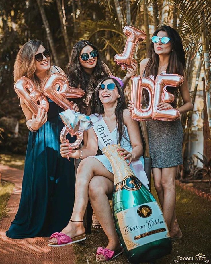 three women are posing for a photo while holding balloons in the shape of letters and numbers