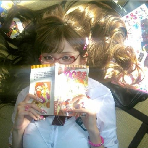 a girl with glasses is holding up a book in front of her face and looking at the camera