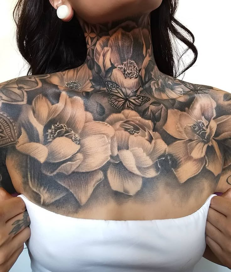 a woman with tattoos on her chest is holding onto the back of her neck and has flowers