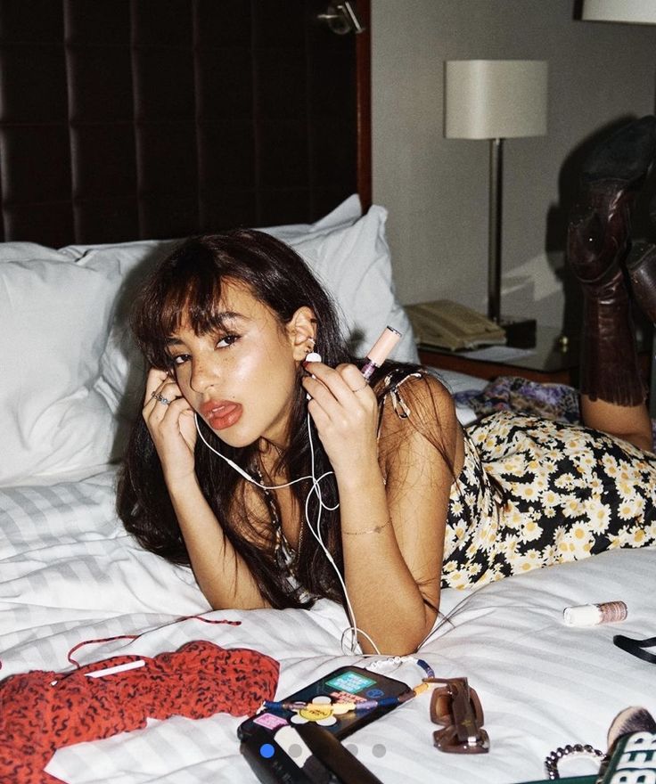 a woman laying on top of a bed with headphones in her ears and ear phones around her neck