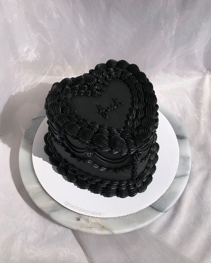 a heart shaped black cake sitting on top of a white plate