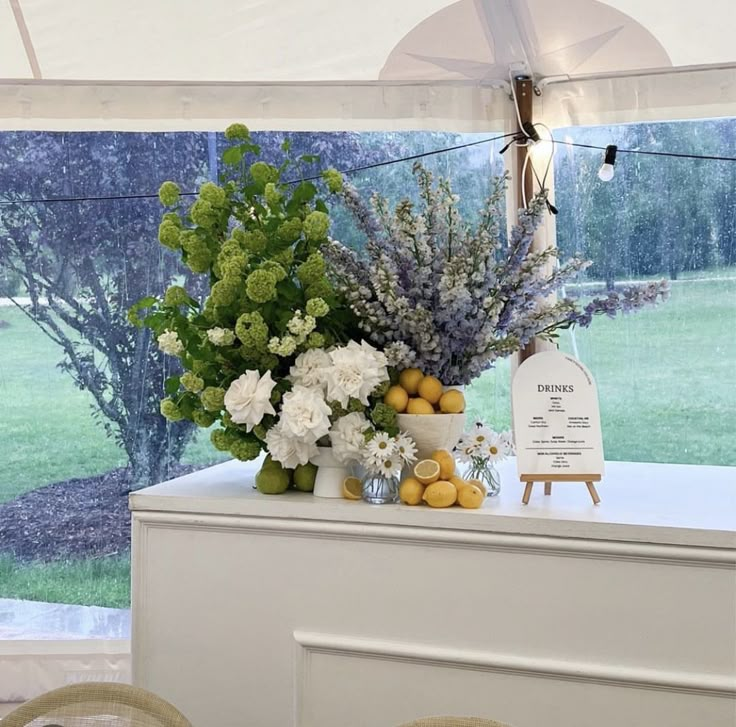 an arrangement of flowers and fruit on display in a tented area at a wedding