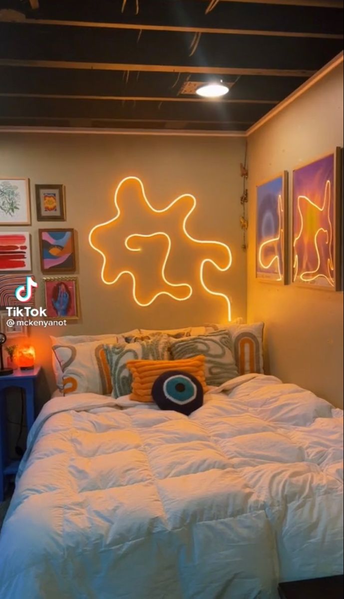 a white bed sitting under a neon sign in a bedroom