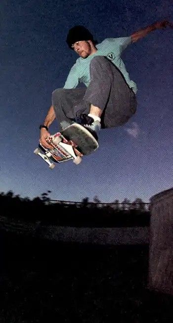 a man flying through the air on top of a skateboard at night with his feet in the air