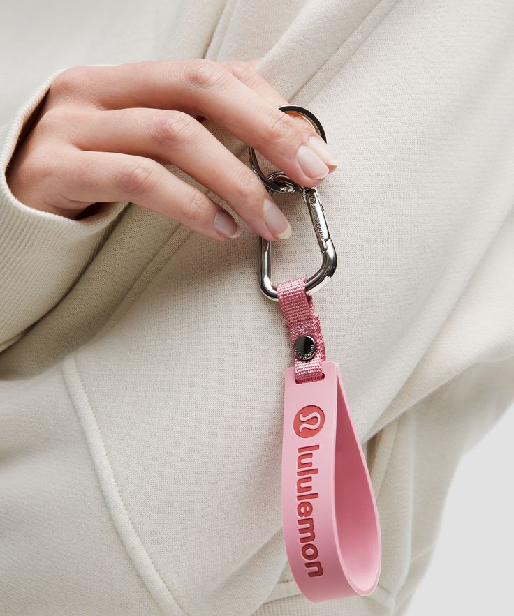 a woman's hand holding onto a pink lanyard with the word on it