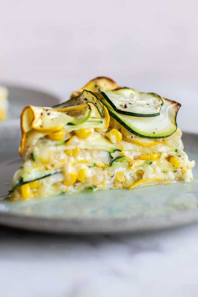 a slice of quiche with zucchini, corn and cheese on a plate