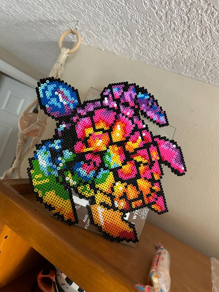 a vase filled with lots of colorful flowers on top of a wooden table next to a wall