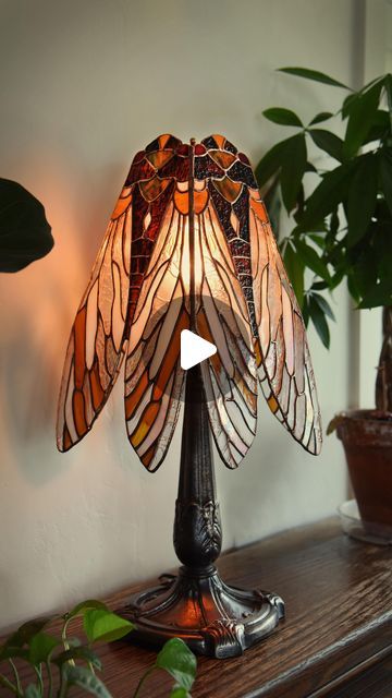 a lamp that is sitting on top of a table next to a potted plant