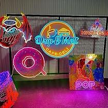 neon signs are displayed in front of a wall with various colors and shapes on it