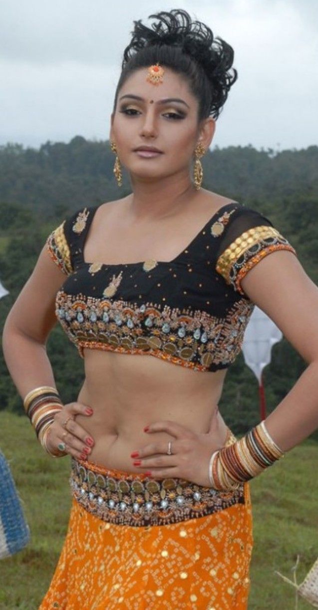 a woman in an orange and black sari is posing for the camera with her hands on her hips