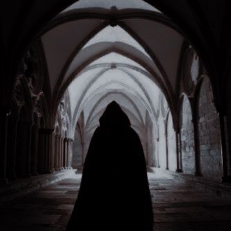 a person in a black cloak walking down a dark hallway with arches and arches on both sides