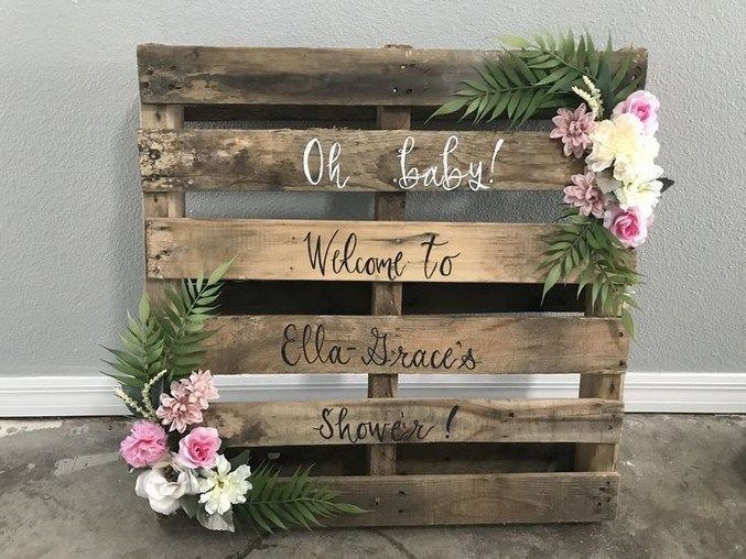 a wooden sign with flowers and greenery on it