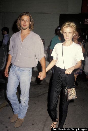 a man and woman holding hands while walking down the street with other people behind them