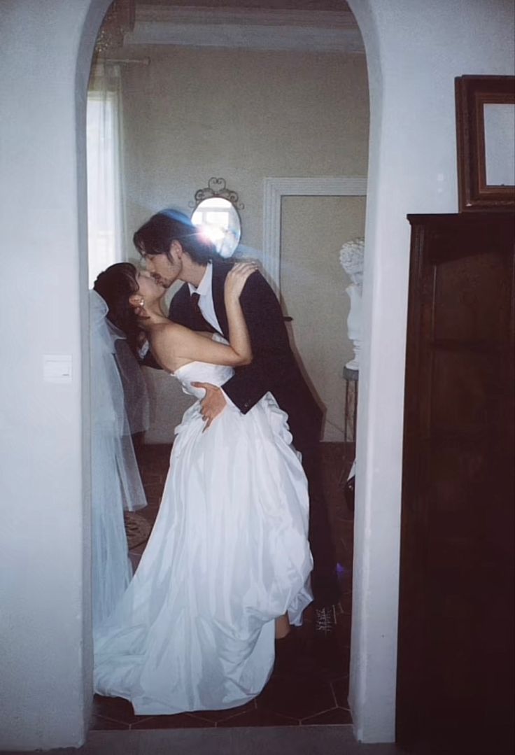 a bride and groom kissing in front of a mirror