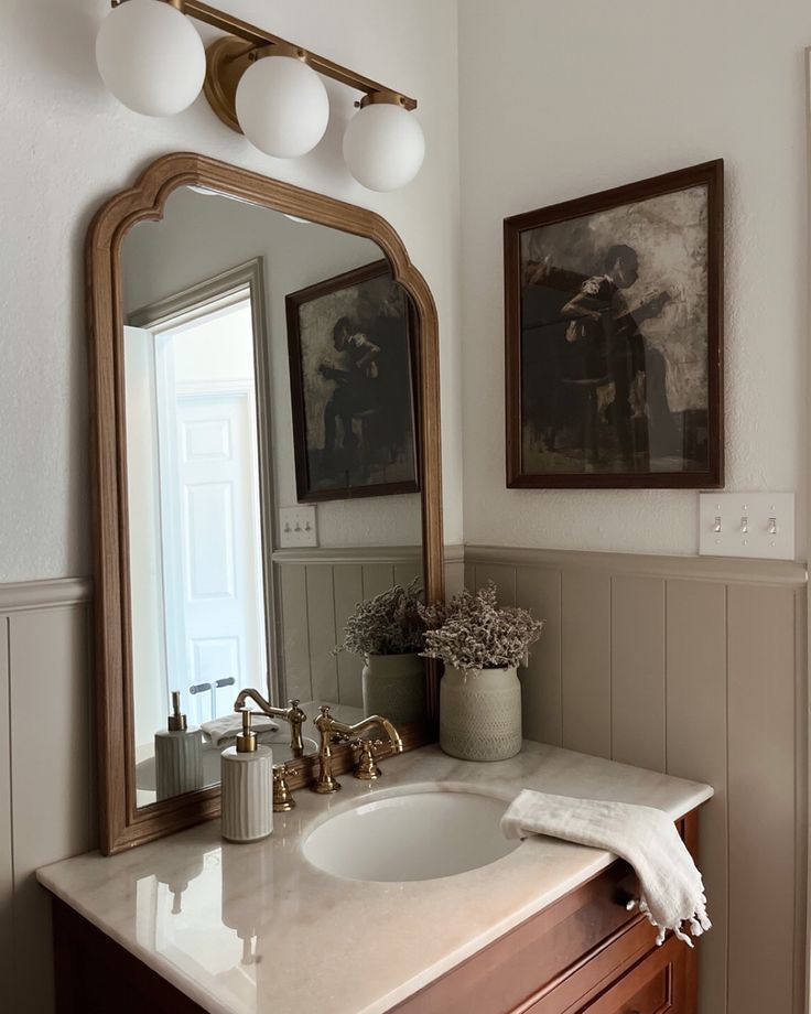 a bathroom with a sink, mirror and pictures on the wall