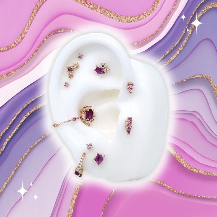 a white plate topped with lots of jewelry on top of a purple and pink background