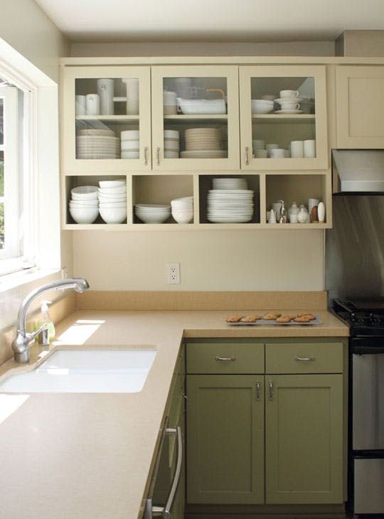 a kitchen with green cabinets and white dishes