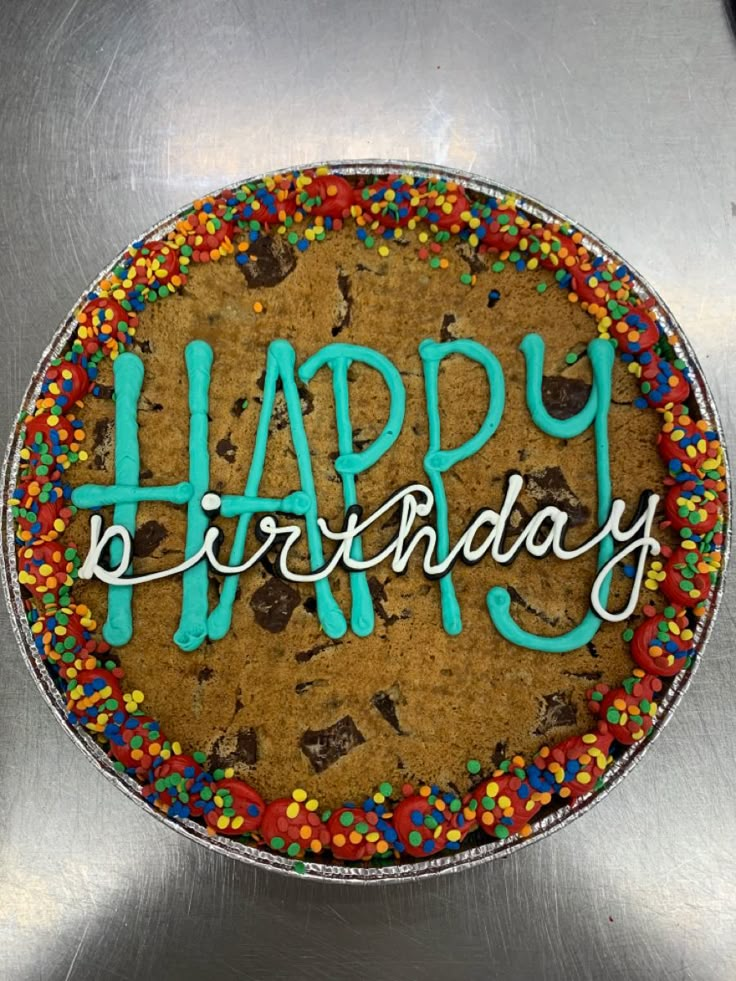 a happy birthday cake with sprinkles and blue frosting on the top