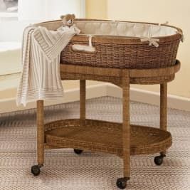 a wicker baby crib with a teddy bear on top and a blanket draped over it