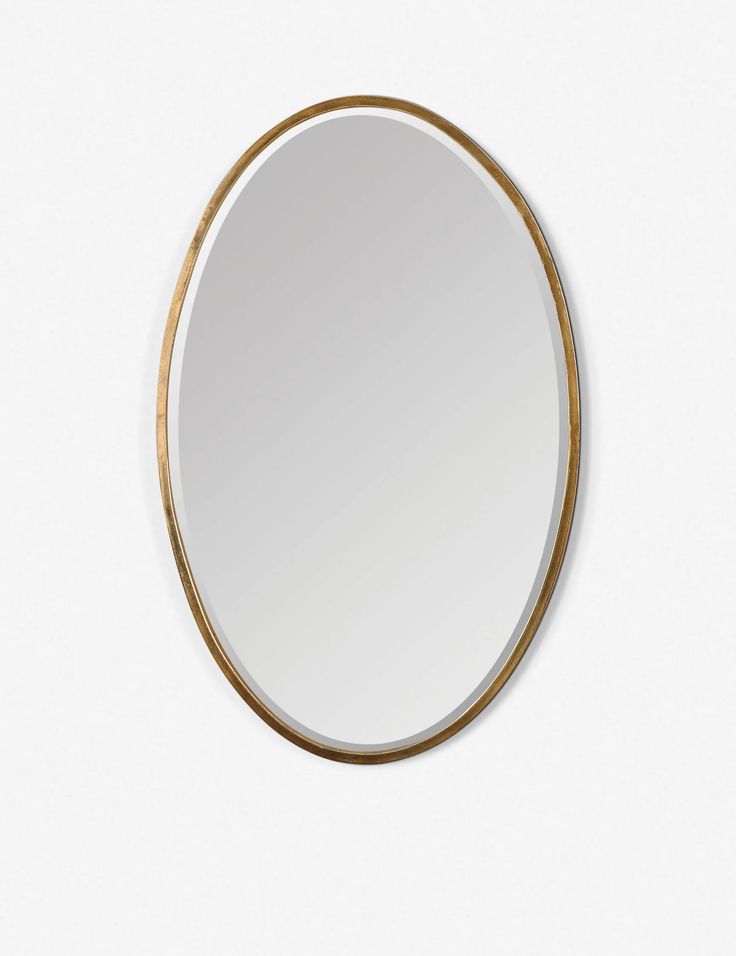 a round mirror on the wall with gold trimmings and a circular frame around it