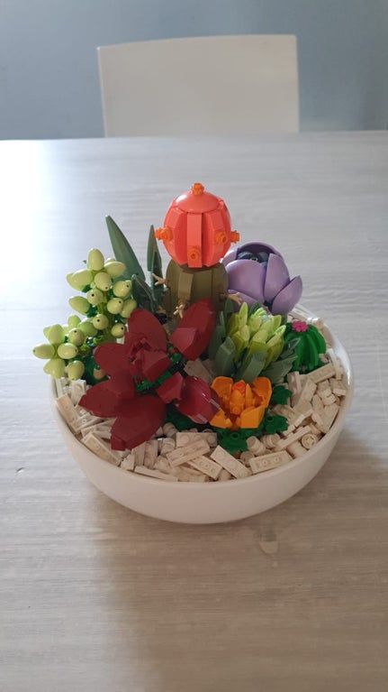 a bowl filled with flowers on top of a wooden table